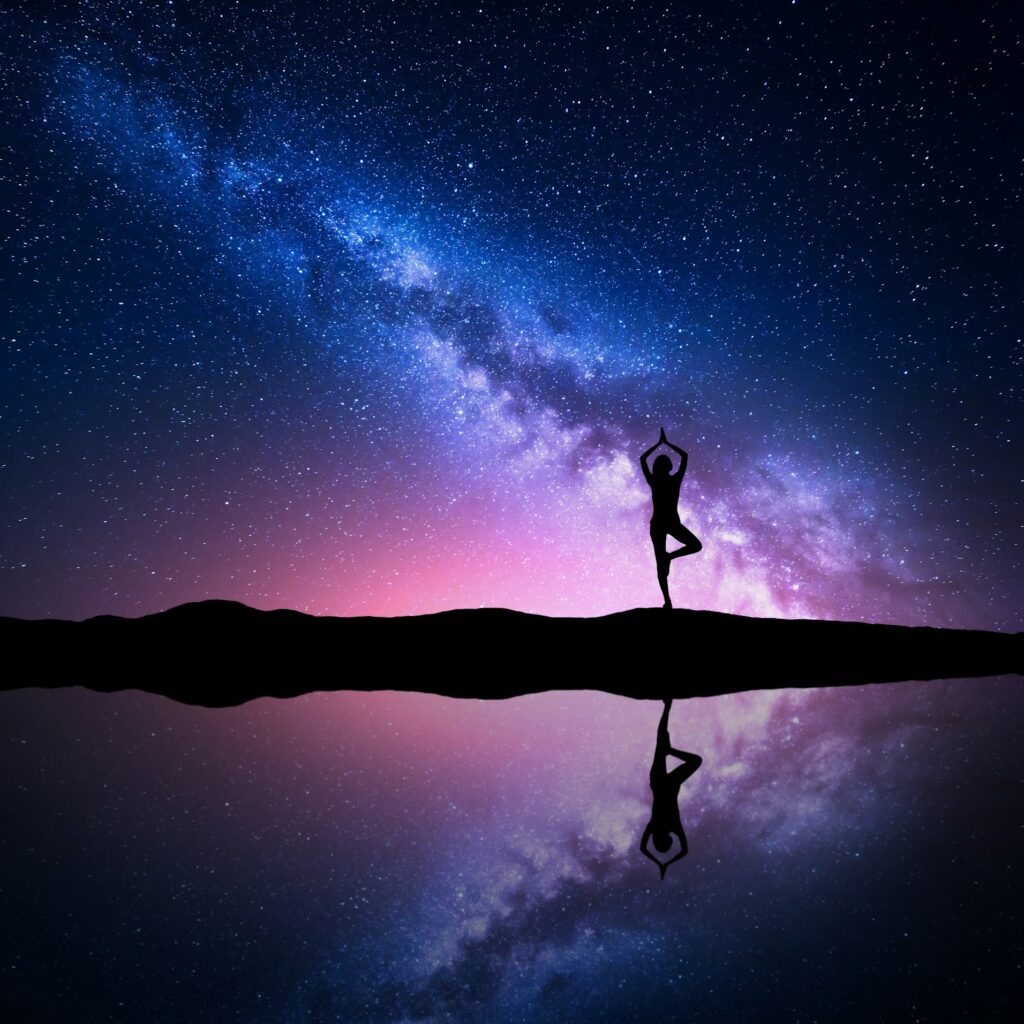Milky Way with silhouette of a standing woman practicing yoga